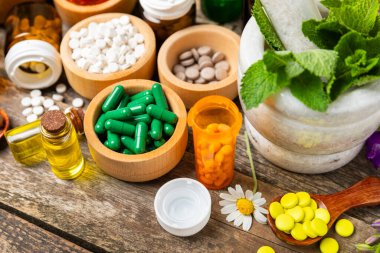 Ahşap zemin üzerinde alternatif ilaç bitkisel kapsül organik ilaç. Bitki ve tablet çeşitleri, vitaminler ve diyet takviyeleri. Sağlıklı yaşam için tıbbi ve şifalı bitkiler.