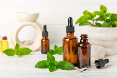 Ahşap bir arka planda esaslı bir nane şekeri. Naneli esaslı yağ ve taze nane yaprakları. Bir şişe aromaterapi yağı. Nane özütü. Doğal kozmetik konsepti, spa bakımı. Boşluğu kopyala