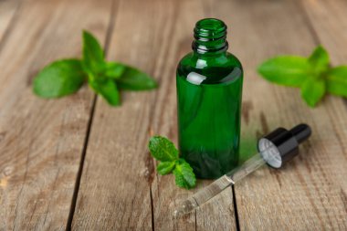 Ahşap bir arka planda esaslı bir nane şekeri. Naneli esaslı yağ ve taze nane yaprakları. Bir şişe aromaterapi yağı. Nane özütü. Doğal kozmetik konsepti, spa bakımı. Boşluğu kopyala