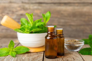 Ahşap bir arka planda esaslı bir nane şekeri. Naneli esaslı yağ ve taze nane yaprakları. Bir şişe aromaterapi yağı. Nane özütü. Doğal kozmetik konsepti, spa bakımı. Boşluğu kopyala