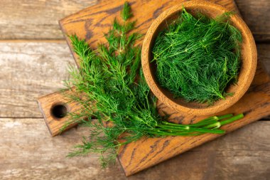 Ahşap arka planda Dill. Taze organik sebzeler. Dill çiftliği. Dereotu yapraklarını kes. Bahar genç deresi sürüsü. Vitaminler. İplik. Aromatik mutfak baharatı. Mesaj için yer. Boşluğu kopyala