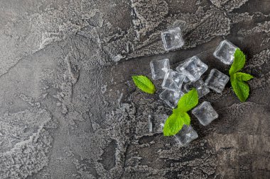 Arka planda nane ve buz var. Yeşil taze nane ve buz küpü. Nane yaprağı, buz küpü ve soğuk içecek için su damlası. Üst Manzara. Mesaj için yer var. Boşluğu kopyala.