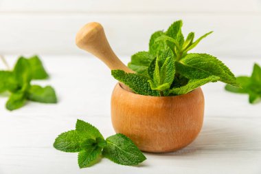 Ahşap zemin üzerinde havan ve kabuk ile taze nane. Melissa gider. Şifalı bitkiler, ilaç için havanda yeşil nane yaprakları. Mesaj için alan. Boşluğu kopyala.