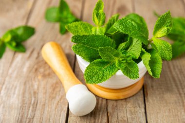 Ahşap zemin üzerinde havan ve kabuk ile taze nane. Melissa gider. Şifalı bitkiler, ilaç için havanda yeşil nane yaprakları. Mesaj için alan. Boşluğu kopyala.