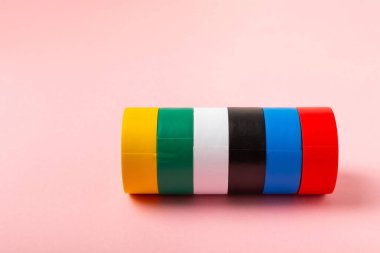 Parlak renkli arka plandaki bant yalıtılıyor. Farklı renkte izolasyon bantları. Yalıtım bandı. İnşaat aletleri. Elektrikçi aletleri. Bir parça koli bandı. Metin için boşluk. Boşluğu kopyala.