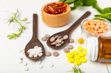 Ahşap zemin üzerinde alternatif ilaç bitkisel kapsül organik ilaç. Bitki ve tablet çeşitleri, vitaminler ve diyet takviyeleri. Sağlıklı yaşam için tıbbi ve şifalı bitkiler.