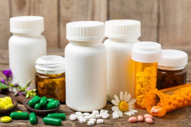Ahşap zemin üzerinde alternatif ilaç bitkisel kapsül organik ilaç. Bitki ve tablet çeşitleri, vitaminler ve diyet takviyeleri. Sağlıklı yaşam için tıbbi ve şifalı bitkiler.