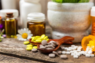 Ahşap zemin üzerinde alternatif ilaç bitkisel kapsül organik ilaç. Bitki ve tablet çeşitleri, vitaminler ve diyet takviyeleri. Sağlıklı yaşam için tıbbi ve şifalı bitkiler.