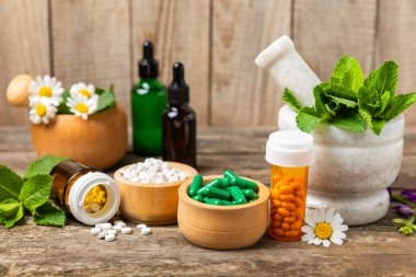 Ahşap zemin üzerinde alternatif ilaç bitkisel kapsül organik ilaç. Bitki ve tablet çeşitleri, vitaminler ve diyet takviyeleri. Sağlıklı yaşam için tıbbi ve şifalı bitkiler.