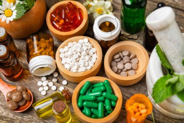 Ahşap zemin üzerinde alternatif ilaç bitkisel kapsül organik ilaç. Bitki ve tablet çeşitleri, vitaminler ve diyet takviyeleri. Sağlıklı yaşam için tıbbi ve şifalı bitkiler.