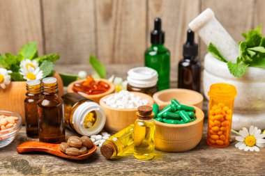 Ahşap zemin üzerinde alternatif ilaç bitkisel kapsül organik ilaç. Bitki ve tablet çeşitleri, vitaminler ve diyet takviyeleri. Sağlıklı yaşam için tıbbi ve şifalı bitkiler.