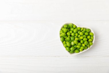 Ahşap zemin üzerinde yeşil bezelyeler olan taze bezelye kabukları. Tatlı yeşil bezelyeler. Yeşil bezelye fasulyesi sebzesi. Vejetaryen. Sağlıklı sebze. Boşluğu kopyala