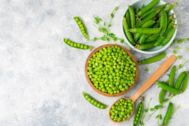 Ahşap zemin üzerinde yeşil bezelyeler olan taze bezelye kabukları. Tatlı yeşil bezelyeler. Yeşil bezelye fasulyesi sebzesi. Vejetaryen. Sağlıklı sebze. Boşluğu kopyala