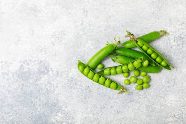 Ahşap zemin üzerinde yeşil bezelyeler olan taze bezelye kabukları. Tatlı yeşil bezelyeler. Yeşil bezelye fasulyesi sebzesi. Vejetaryen. Sağlıklı sebze. Boşluğu kopyala