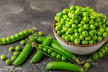 Ahşap zemin üzerinde yeşil bezelyeler olan taze bezelye kabukları. Tatlı yeşil bezelyeler. Yeşil bezelye fasulyesi sebzesi. Vejetaryen. Sağlıklı sebze. Boşluğu kopyala