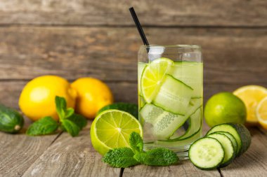 Salatalık suyu, limon, nane ve ahşap bir masada. İçme bardağında dilimlenmiş salatalık ile karıştırılmış su. Tonik ferahlatıcı bir içecek. Salatalık limonata. Doğal soğutma içeceği. Boşluğu kopyala.