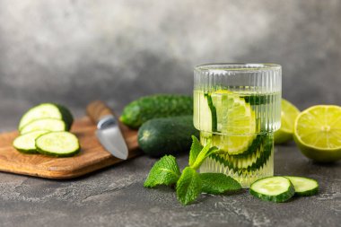 Salatalık suyu, limon, nane ve ahşap bir masada. İçme bardağında dilimlenmiş salatalık ile karıştırılmış su. Tonik ferahlatıcı bir içecek. Salatalık limonata. Doğal soğutma içeceği. Boşluğu kopyala.