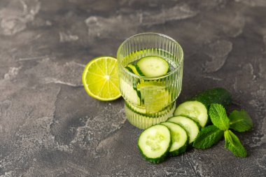 Salatalık suyu, limon, nane ve ahşap bir masada. İçme bardağında dilimlenmiş salatalık ile karıştırılmış su. Tonik ferahlatıcı bir içecek. Salatalık limonata. Doğal soğutma içeceği. Boşluğu kopyala.