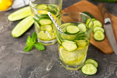 Salatalık suyu, limon, nane ve ahşap bir masada. İçme bardağında dilimlenmiş salatalık ile karıştırılmış su. Tonik ferahlatıcı bir içecek. Salatalık limonata. Doğal soğutma içeceği. Boşluğu kopyala.