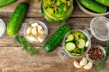 Ahşap bir arka planda kavanozda taze tuzlanmış ev yapımı salatalıklar. Dereotlu, sarımsaklı ve biberli salatalık turşusu. Konserve salatalık, salatalık ve penis. Ev yapımı koruma..