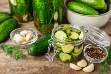 Ahşap bir arka planda kavanozda taze tuzlanmış ev yapımı salatalıklar. Dereotlu, sarımsaklı ve biberli salatalık turşusu. Konserve salatalık, salatalık ve penis. Ev yapımı koruma..