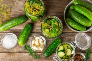 Ahşap bir arka planda kavanozda taze tuzlanmış ev yapımı salatalıklar. Dereotlu, sarımsaklı ve biberli salatalık turşusu. Konserve salatalık, salatalık ve penis. Ev yapımı koruma..