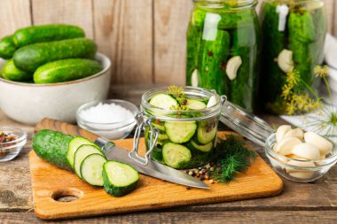 Ahşap bir arka planda kavanozda taze tuzlanmış ev yapımı salatalıklar. Dereotlu, sarımsaklı ve biberli salatalık turşusu. Konserve salatalık, salatalık ve penis. Ev yapımı koruma..