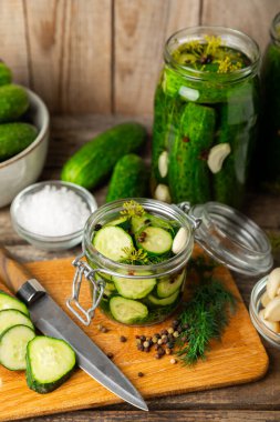 Ahşap bir arka planda kavanozda taze tuzlanmış ev yapımı salatalıklar. Dereotlu, sarımsaklı ve biberli salatalık turşusu. Konserve salatalık, salatalık ve penis. Ev yapımı koruma..