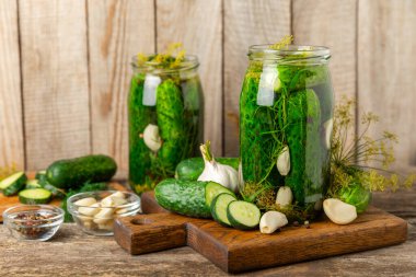 Ahşap bir arka planda kavanozda taze tuzlanmış ev yapımı salatalıklar. Dereotlu, sarımsaklı ve biberli salatalık turşusu. Konserve salatalık, salatalık ve penis. Ev yapımı koruma..
