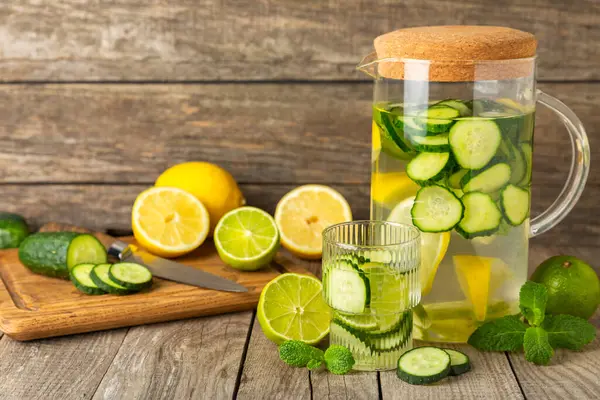 Salatalık suyu, limon, nane ve ahşap bir masada. İçme bardağında dilimlenmiş salatalık ile karıştırılmış su. Tonik ferahlatıcı bir içecek. Salatalık limonata. Doğal soğutma içeceği. Boşluğu kopyala.