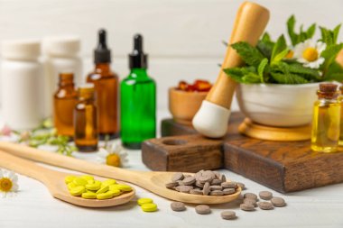 Ahşap zemin üzerinde alternatif ilaç bitkisel kapsül organik ilaç. Bitki ve tablet çeşitleri, vitaminler ve diyet takviyeleri. Sağlıklı yaşam için tıbbi ve şifalı bitkiler.