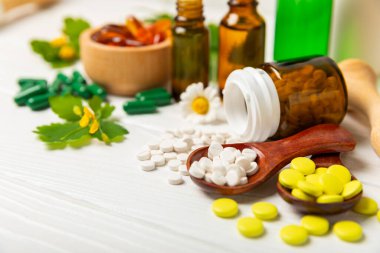 Ahşap zemin üzerinde alternatif ilaç bitkisel kapsül organik ilaç. Bitki ve tablet çeşitleri, vitaminler ve diyet takviyeleri. Sağlıklı yaşam için tıbbi ve şifalı bitkiler.