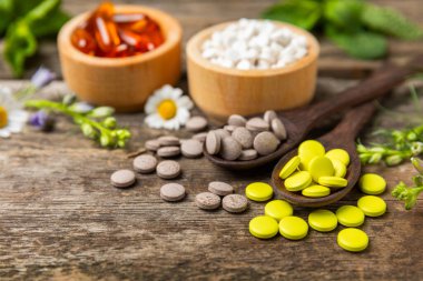 Ahşap zemin üzerinde alternatif ilaç bitkisel kapsül organik ilaç. Bitki ve tablet çeşitleri, vitaminler ve diyet takviyeleri. Sağlıklı yaşam için tıbbi ve şifalı bitkiler.