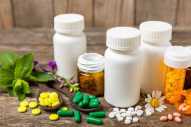 Ahşap zemin üzerinde alternatif ilaç bitkisel kapsül organik ilaç. Bitki ve tablet çeşitleri, vitaminler ve diyet takviyeleri. Sağlıklı yaşam için tıbbi ve şifalı bitkiler.