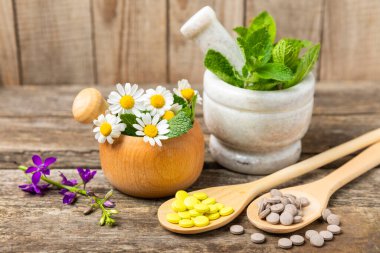 Ahşap zemin üzerinde alternatif ilaç bitkisel kapsül organik ilaç. Bitki ve tablet çeşitleri, vitaminler ve diyet takviyeleri. Sağlıklı yaşam için tıbbi ve şifalı bitkiler.