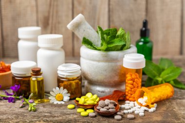 Ahşap zemin üzerinde alternatif ilaç bitkisel kapsül organik ilaç. Bitki ve tablet çeşitleri, vitaminler ve diyet takviyeleri. Sağlıklı yaşam için tıbbi ve şifalı bitkiler.