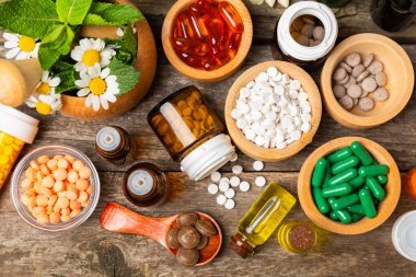 Ahşap zemin üzerinde alternatif ilaç bitkisel kapsül organik ilaç. Bitki ve tablet çeşitleri, vitaminler ve diyet takviyeleri. Sağlıklı yaşam için tıbbi ve şifalı bitkiler.