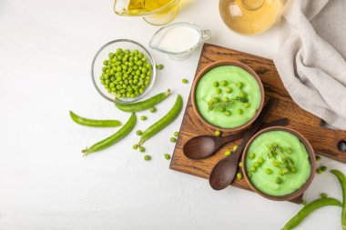 Ahşap bir masada yeşil bezelye çorbası. Taze bezelye çorbası kasesi. Yeşil bezelye ve kızarmış ekmekle dolu bir kasede lezzetli, sağlıklı krema çorbası. Sağlıklı vejetaryen püresi. Uzayı kopyala Metin için boşluk.