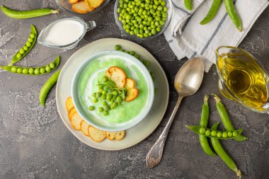 Ahşap bir masada yeşil bezelye çorbası. Taze bezelye çorbası kasesi. Yeşil bezelye ve kızarmış ekmekle dolu bir kasede lezzetli, sağlıklı krema çorbası. Sağlıklı vejetaryen püresi. Uzayı kopyala Metin için boşluk.