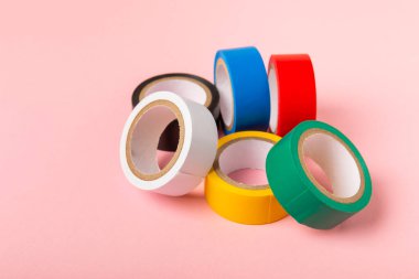 Parlak renkli arka plandaki bant yalıtılıyor. Farklı renkte izolasyon bantları. Yalıtım bandı. İnşaat aletleri. Elektrikçi aletleri. Bir parça koli bandı. Metin için boşluk. Boşluğu kopyala.