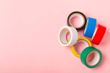 Parlak renkli arka plandaki bant yalıtılıyor. Farklı renkte izolasyon bantları. Yalıtım bandı. İnşaat aletleri. Elektrikçi aletleri. Bir parça koli bandı. Metin için boşluk. Boşluğu kopyala.