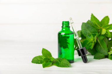 Ahşap bir arka planda esaslı bir nane şekeri. Naneli esaslı yağ ve taze nane yaprakları. Bir şişe aromaterapi yağı. Nane özütü. Doğal kozmetik konsepti, spa bakımı. Boşluğu kopyala