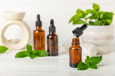 Ahşap bir arka planda esaslı bir nane şekeri. Naneli esaslı yağ ve taze nane yaprakları. Bir şişe aromaterapi yağı. Nane özütü. Doğal kozmetik konsepti, spa bakımı. Boşluğu kopyala