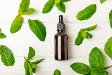 Ahşap bir arka planda esaslı bir nane şekeri. Naneli esaslı yağ ve taze nane yaprakları. Bir şişe aromaterapi yağı. Nane özütü. Doğal kozmetik konsepti, spa bakımı. Boşluğu kopyala