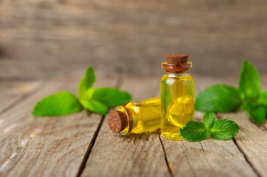 Ahşap bir arka planda esaslı bir nane şekeri. Naneli esaslı yağ ve taze nane yaprakları. Bir şişe aromaterapi yağı. Nane özütü. Doğal kozmetik konsepti, spa bakımı. Boşluğu kopyala