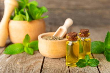 Ahşap bir arka planda esaslı bir nane şekeri. Naneli esaslı yağ ve taze nane yaprakları. Bir şişe aromaterapi yağı. Nane özütü. Doğal kozmetik konsepti, spa bakımı. Boşluğu kopyala