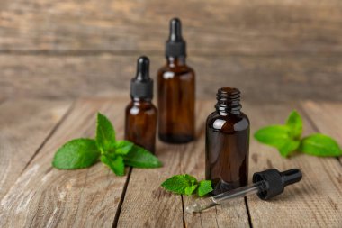 Ahşap bir arka planda esaslı bir nane şekeri. Naneli esaslı yağ ve taze nane yaprakları. Bir şişe aromaterapi yağı. Nane özütü. Doğal kozmetik konsepti, spa bakımı. Boşluğu kopyala