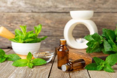 Ahşap bir arka planda esaslı bir nane şekeri. Naneli esaslı yağ ve taze nane yaprakları. Bir şişe aromaterapi yağı. Nane özütü. Doğal kozmetik konsepti, spa bakımı. Boşluğu kopyala