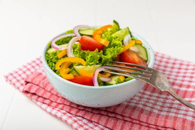 Ahşap bir arka planda salatalık. Taze sebzeli, salatalıklı, domatesli, tatlı biberli ve salatalı ev yapımı salata. Vejetaryen bahar salatası.