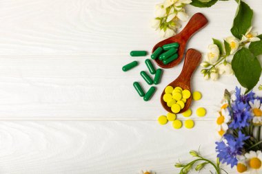 Ahşap zemin üzerinde alternatif ilaç bitkisel kapsül organik ilaç. Bitki ve tablet çeşitleri, vitaminler ve diyet takviyeleri. Sağlıklı yaşam için tıbbi ve şifalı bitkiler.